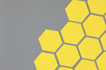 Trendy Abstract diagonal geometric composition with bright yellow paper hexagons on neutral gray background with copy space for text. Flat lay, top view. Year color trend