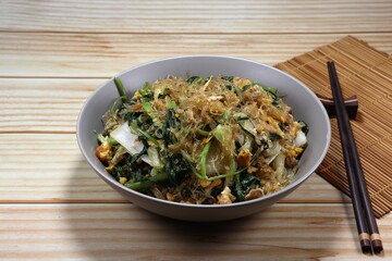 Fried and stirred spicy vermicelli mixed with fresh vegetable and seasoning with local sauce on the plate. Famous traditional noodle menu in Asia restaurant. 