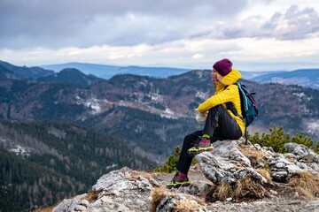 Hiker woman in a yellow down jacket enjoing the view.