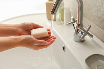 Woman washing hands in bathroom sink with soap