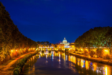 Fototapeta premium Sant' Angelo Bridge and St. Peter's cathedral at night in Vatican City, Rome.Italy