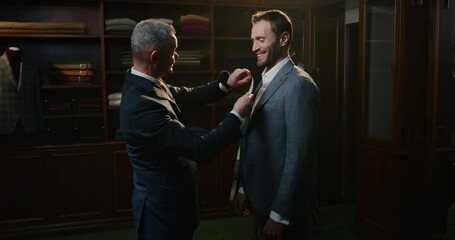 Cinematic shot of professional tailor taking measurements of client for creation custom tailored suit in a luxury tailoring atelier. Concept of fashion, handmade, hand craft, couturier and business.