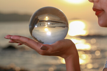 .lady catch the crystal ball on her hand beside Patong beach during sunset