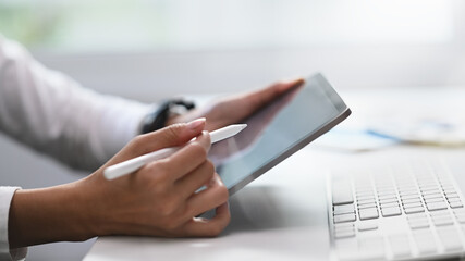 Close up view of male graphic designer or photo editor working on digital tablet in studio office.