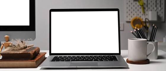 Front view of laptop on creative designer workspace. Blank screen for your information.