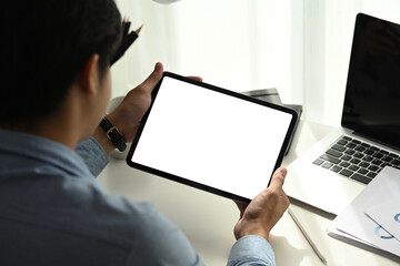 Rear view of young man working on tablet portable electronic device and looking for information...