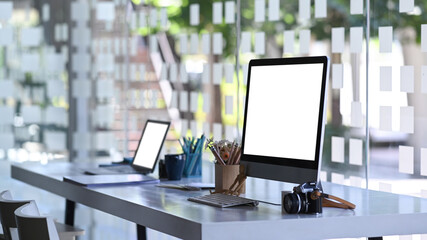 Side view of photographer workstation with modern multiple devices mockup on white office table.