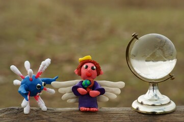 An angel figurine and a small glass globe. Next to the figure of the virus.