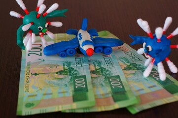 The figure of the virus on banknotes. Near a toy plane.
