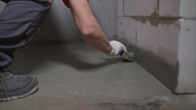 Waterproofing the floor with a mixture. Hand mixes waterproofing mortar in a bucket. Male hand holding a brush to apply waterproofing to the floor. Waterproofing solution in a bucket.