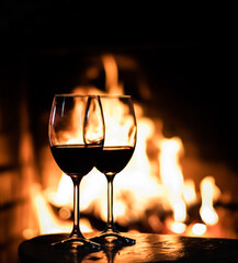 Two glasses of red wine on the background of fireplace lights