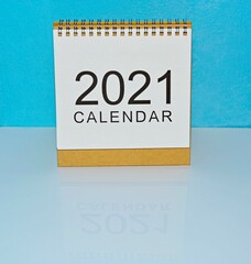 Year 2021 white calendar with blue backgrounds on a white desk