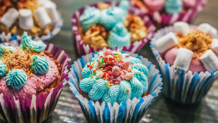 Cupcakes blue pink buttercream decorated with sprinkles, marshmallow closeup. Birthday party banner...