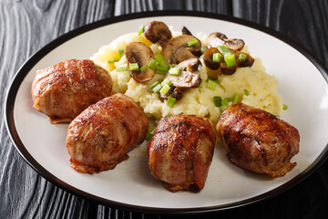 Slavink is a traditional Dutch dish consisting of meat that is wrapped in bacon and fried served with mashed potatoes and mushrooms closeup in the plate on the table. horizontal