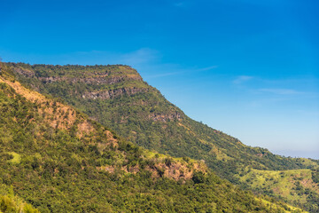 Obraz premium Mountain view morning on top hills and green forest cover with soft mist and blue sky background.Thailand.