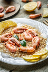 Appetizing delicious frozen dish of shrimps and rice with lemon on a wooden table. Concept of ready made frozen food for dinner like in a restaurant at home