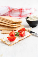 Healthy crisp rye bread with soft cheese, chive and cherry tomatoes selective focus on a light background. Healthy breakfast.
