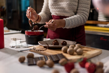 Vegan chef girl cooking sweets wearing santa hat with christmas decoration in christmas kitchen eating chocolates