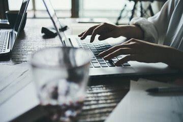 リモートワークでパソコンのキーボードを打つ女性の手元
