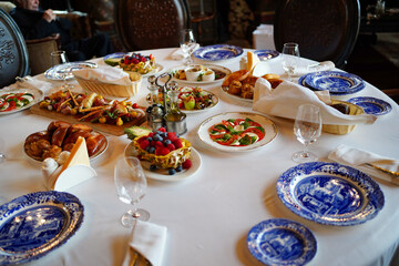 table served with appetizers, plates with a blue pattern and glasses for wine. 