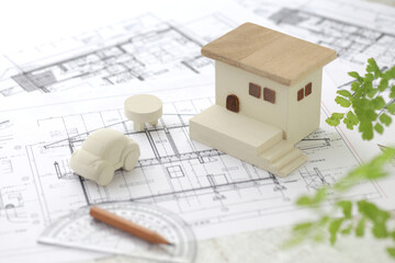 木でできた家の模型とマイホームの設計図のイメージ