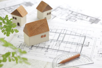 木でできた家の模型とマイホームの設計図のイメージ