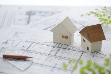木でできた家の模型とマイホームの設計図のイメージ