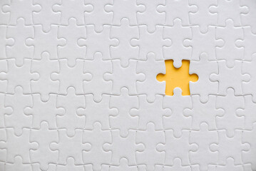 Top view of an empty space of white jigsaw puzzle on a yellow background.