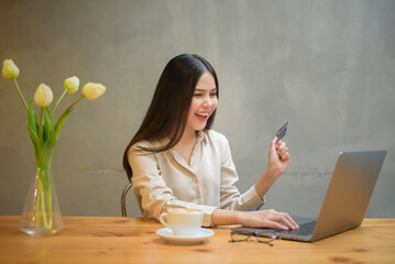 Beautiful woman is online shopping with credit card in coffee shop