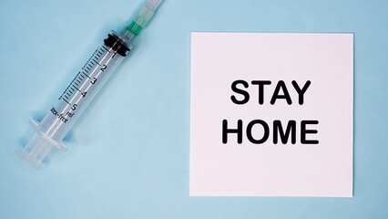 'Stay home' message on sticker with syringe near. Medical concept.