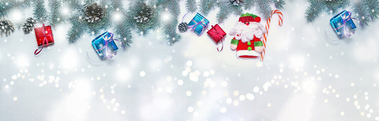 Holiday banner Green Natural Christmas spruce with red and blue gift on a light wooden background. Background happy New year Greeting card Xmas Winter theme Copy space . Snowfall