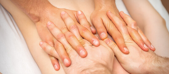4 hands massage the patient back. Two masseurs doing massage. Closeup