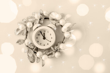white Christmas clock and Christmas wreath on the background of the color champagne Set Sail . Top view, copy space