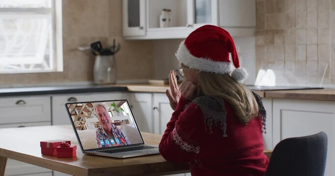 Caucasian woman wearing santa hat on laptop video call during christmas at home