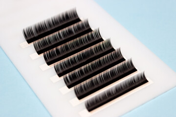 Tweezers remove lashes from the artificial lash tape. The work of a lashmaker.