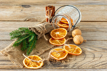 Christmas composition with spruce tree branches, cinnamon sticks and garland made of dried slices of oranges on wooden background. Rustic style.