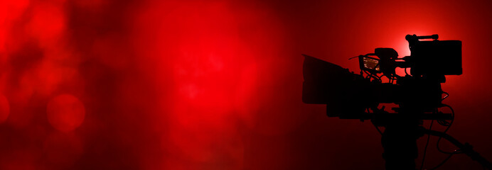video camera in the dark banner with red light bokeh, movie or television background with copy space