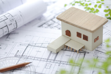 木でできた家の模型とマイホームの設計図のイメージ