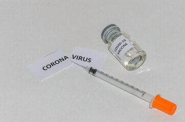 Ampoule with covid-19 coronavirus vaccine and syringe for injections on a white background