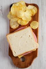 Homemade Bologna and Cheese Sandwich on a rustic wooden board on a white wooden background,...
