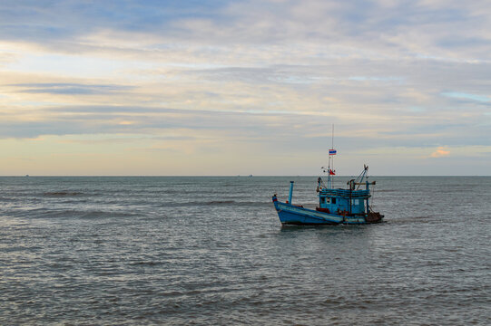A lonely wooden fishing boat returns to the village after night catching at dawn