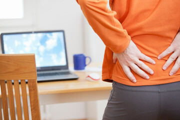 Man with backache working remotely from home with laptop