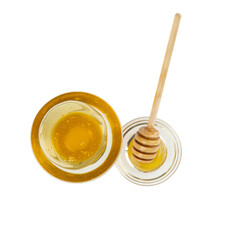 Glass bowl of pure honey with honey dipper isolated on white background.