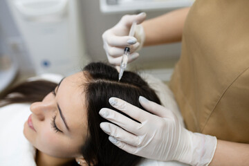 Beautiful woman getting injection for hair growth. Regenerate hair with growth factor injections.