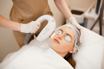 Young beautiful woman on beauty cosmetology procedure in spa salon. Therapist beautician makes a...