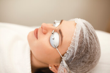 Woman getting laser face treatment in medical spa center by a doctor-cosmetologist in special...
