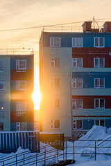 Bright sunlight between colorful residential buildings. City landscape at sunset. A city in the far North of Russia in the Arctic. Cold winter weather. Anadyr, Chukotka, Russian Far East.