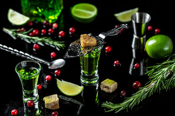 shot glasses with absinthe. Strong alcohol. Absinthe with brown sugar, cranberries, ice cubes and...