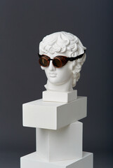 Plaster head of Antinous with round glasses. The concept of the absurd and the combination of the...