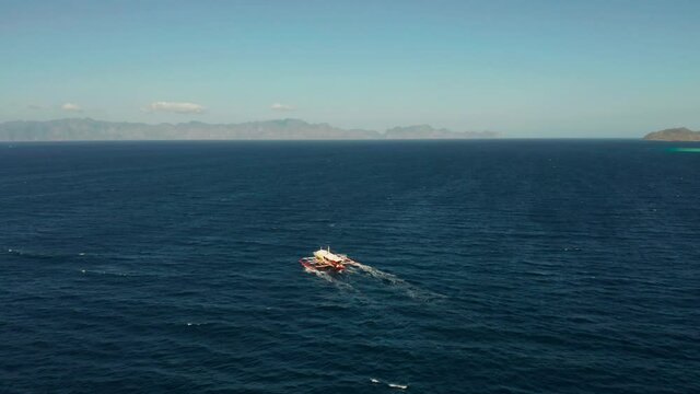 Aerial view tour boat in sea. Seascape blue sea and tropical islands. traditional Filipino wooden outrigger boat called a banca . Motorboat crossing ocean. Banca boat in the Philippines Palawan